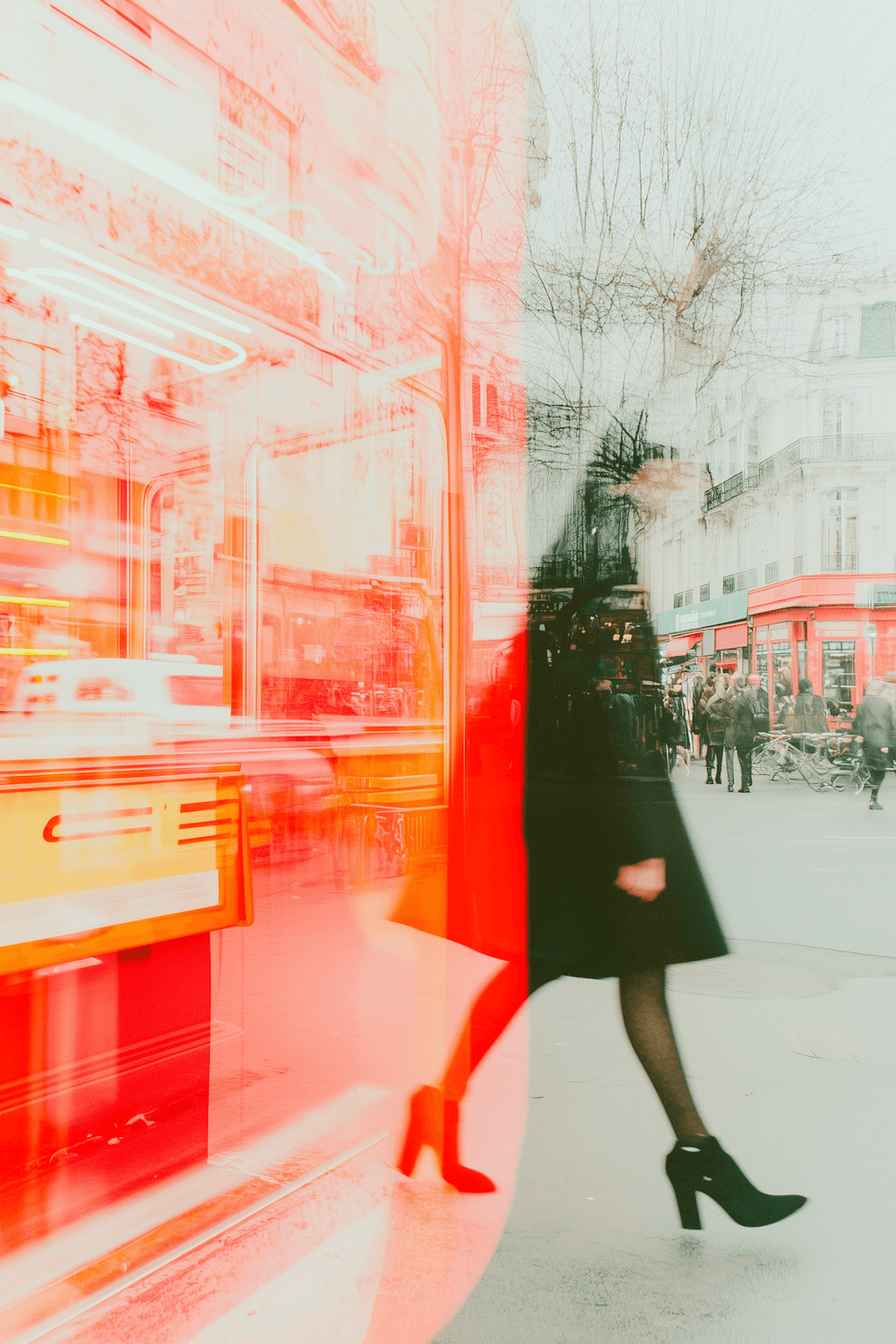 A woman in a black coat striding past a lit shopfront