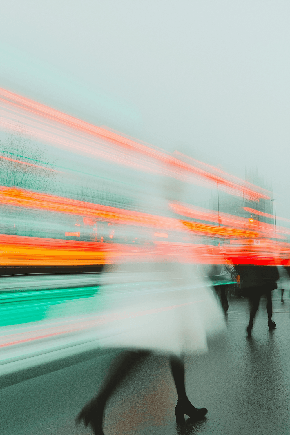 A figure walking through a foggy street streaked with city lights
