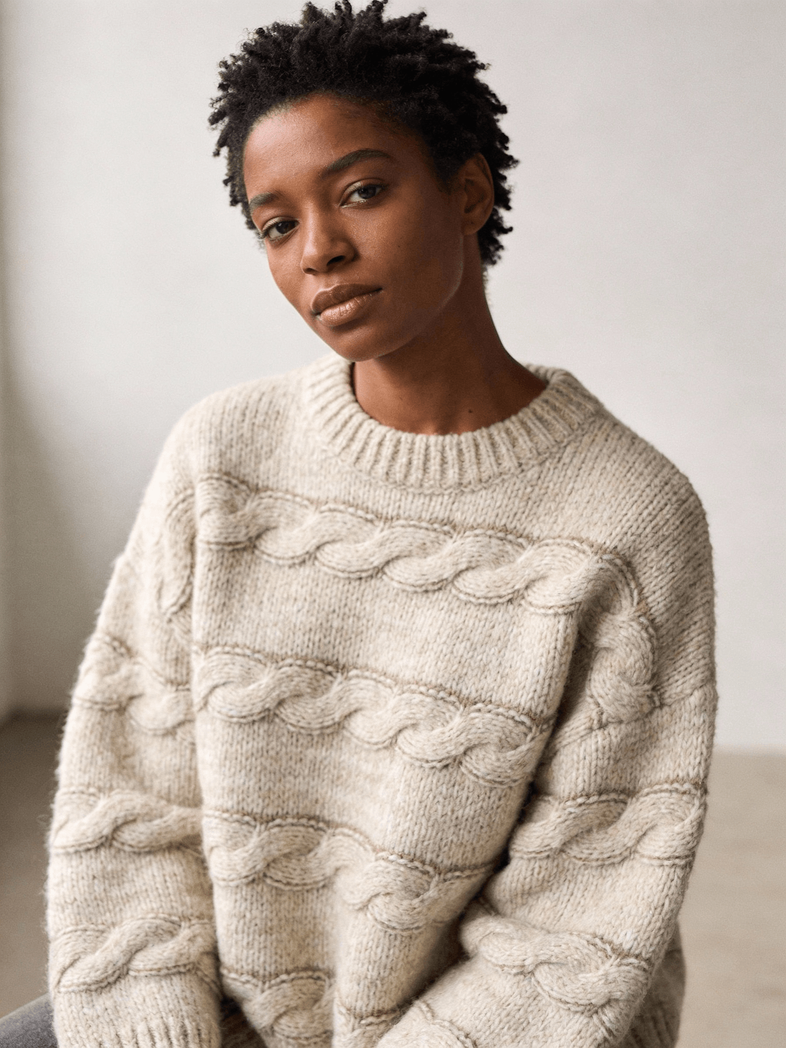 A model in a textured crew-neck knit in soft window light
