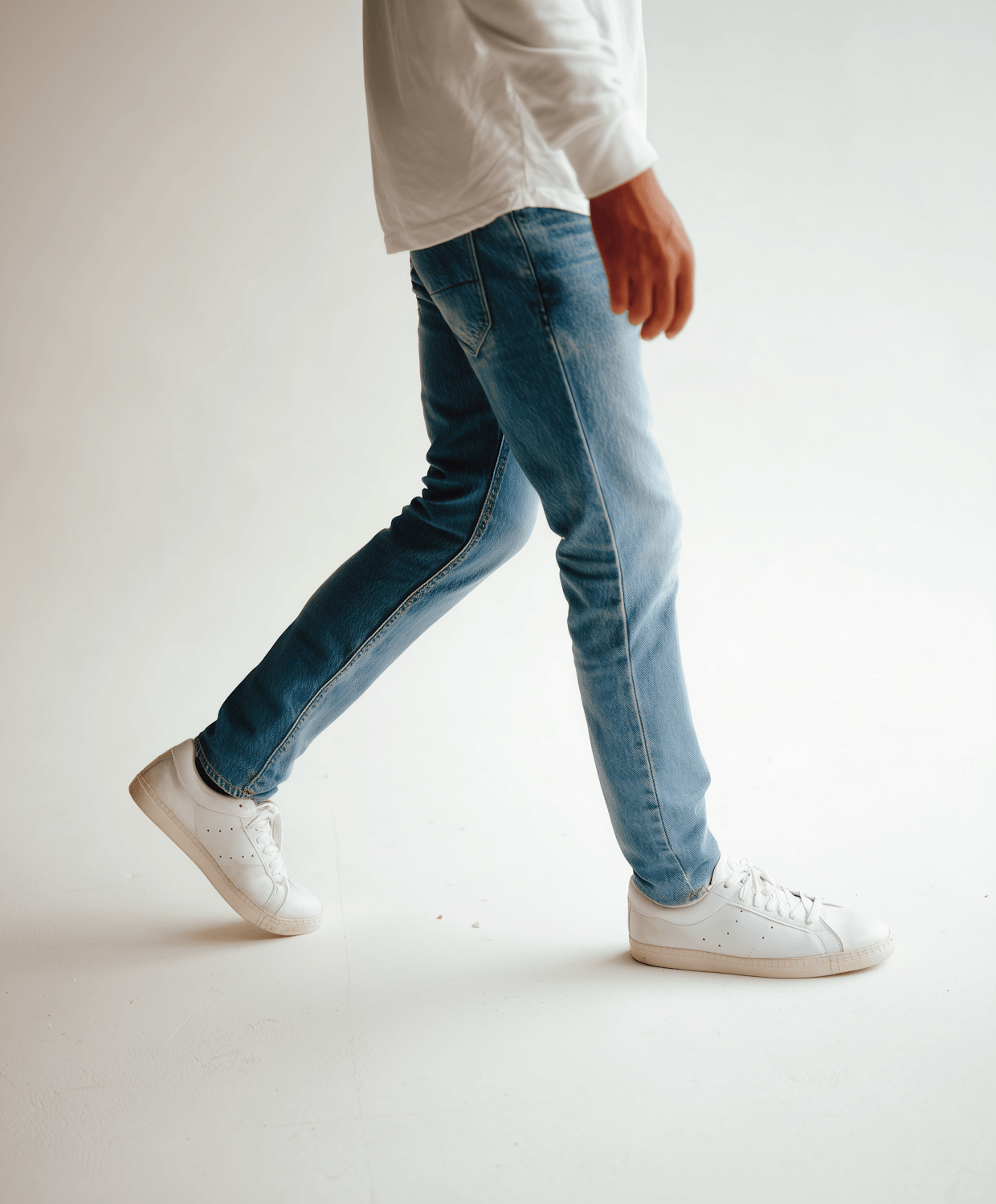 A model walking in wide-leg jeans and white sneakers