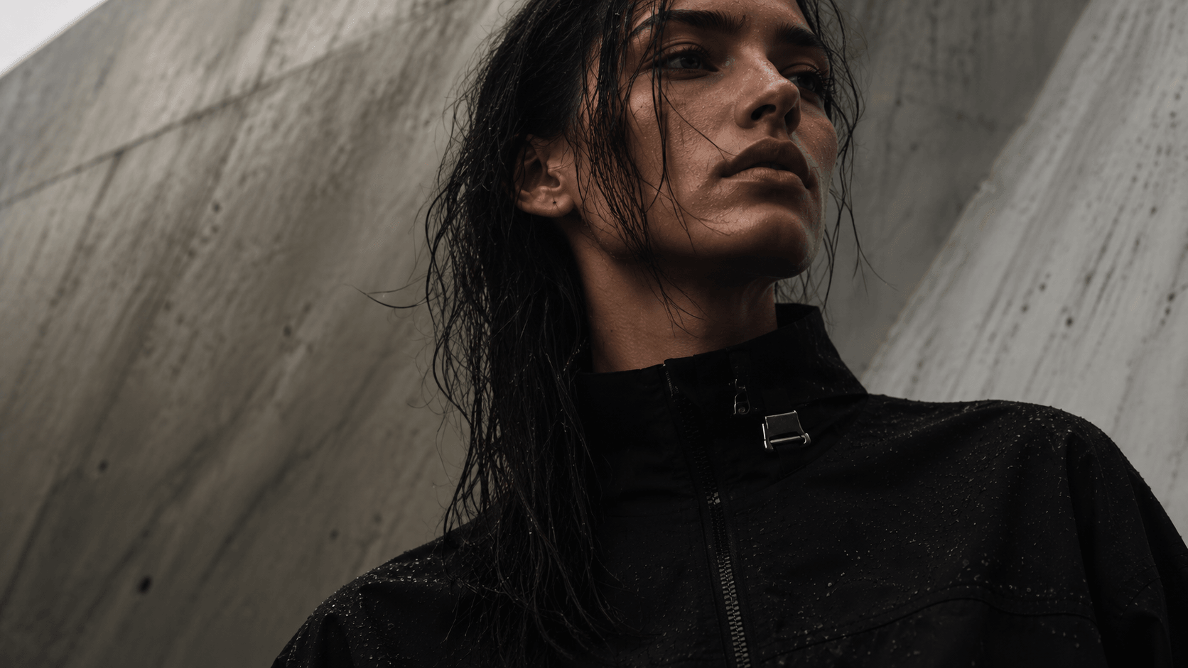 Mara Okonkwo in a black shell jacket against a concrete wall