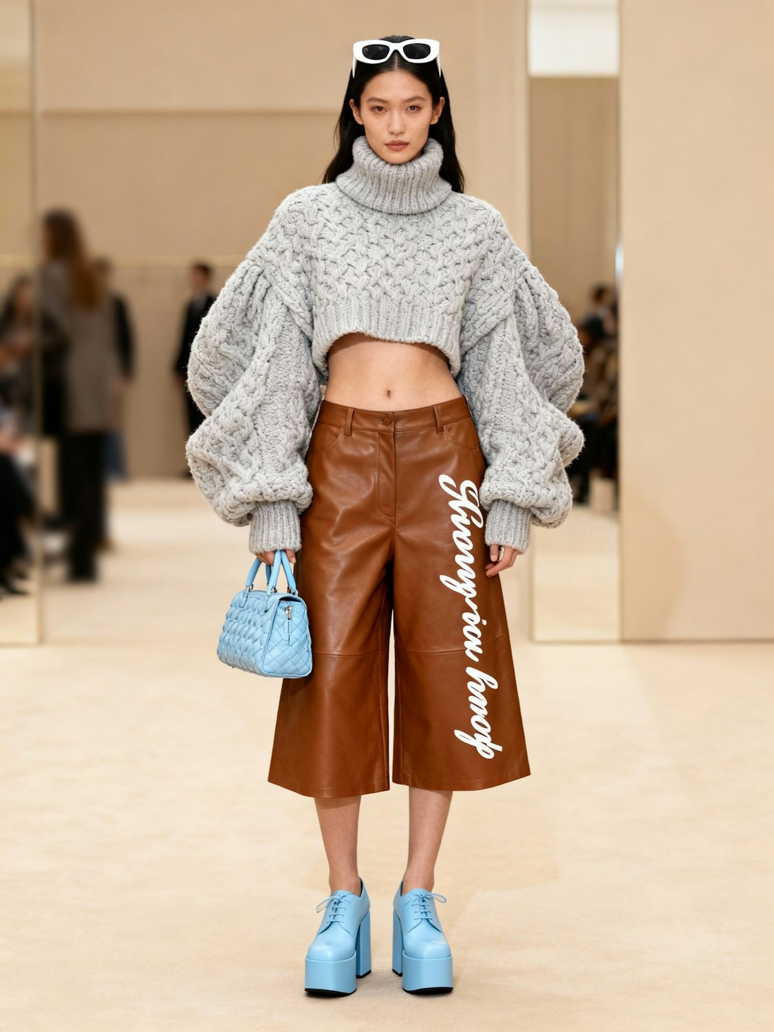 A model in a grey knit standing in a bare room
